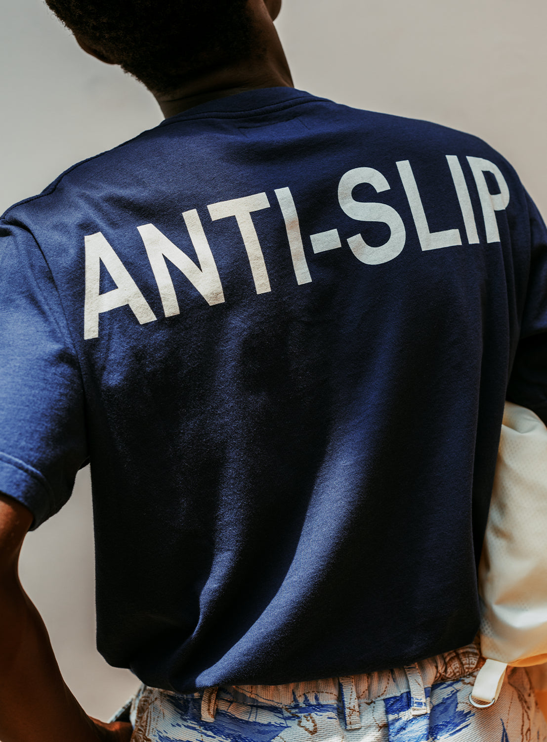Model wearing a navy blue crew neck t-shirt with the text 'ANTI-SLIP' printed in white on the back.
