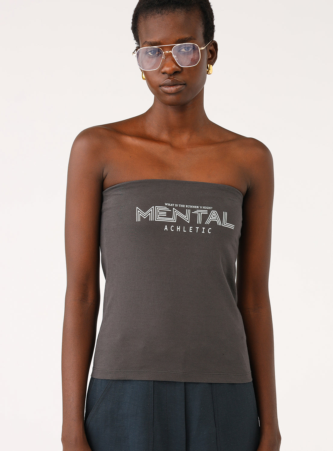 Full body shot of a model wearing a grey tube top with navy wide-leg pants and sunglasses.