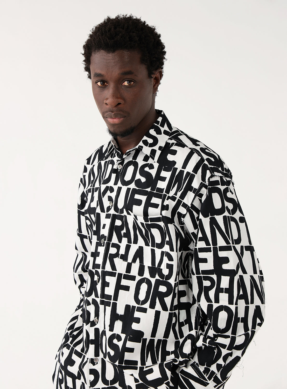 Model wearing a black and white printed shirt, showcasing the subtle organic texture of the LYRIA silk-blend fabric.