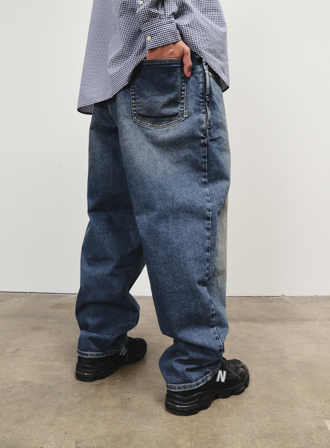 Close-up of the denim pants, showing a loose fit and subtle functional touches.