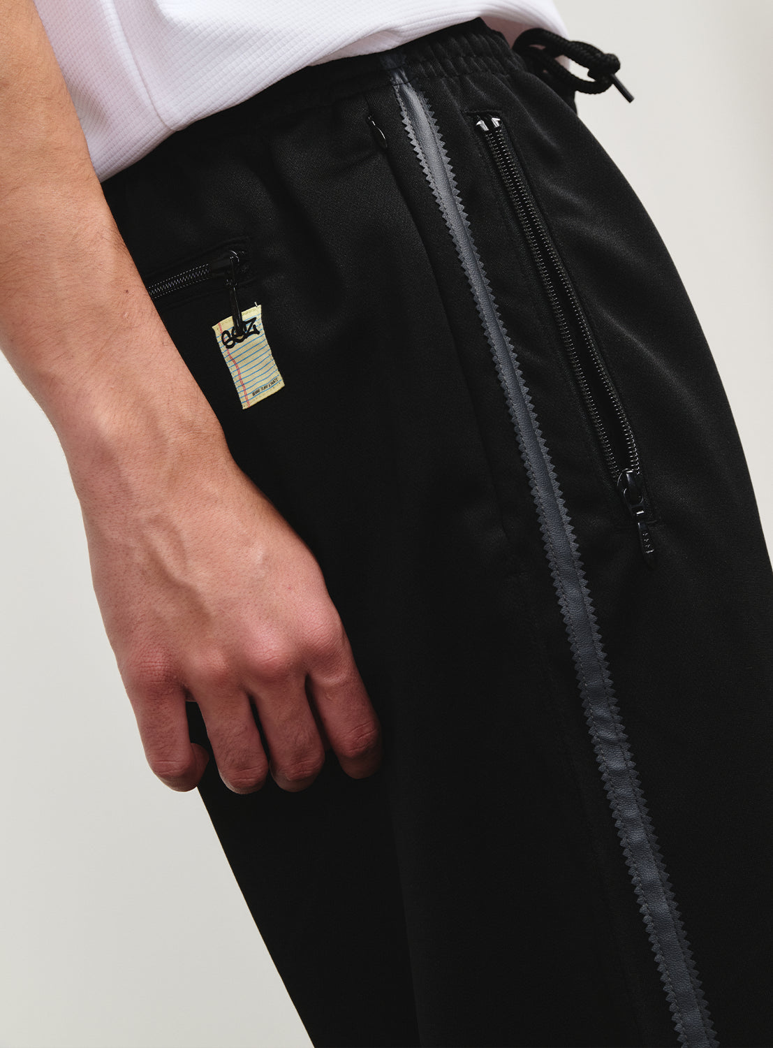 Close-up of the track pants' zippered front pocket, with a subtle SSZ logo underneath.