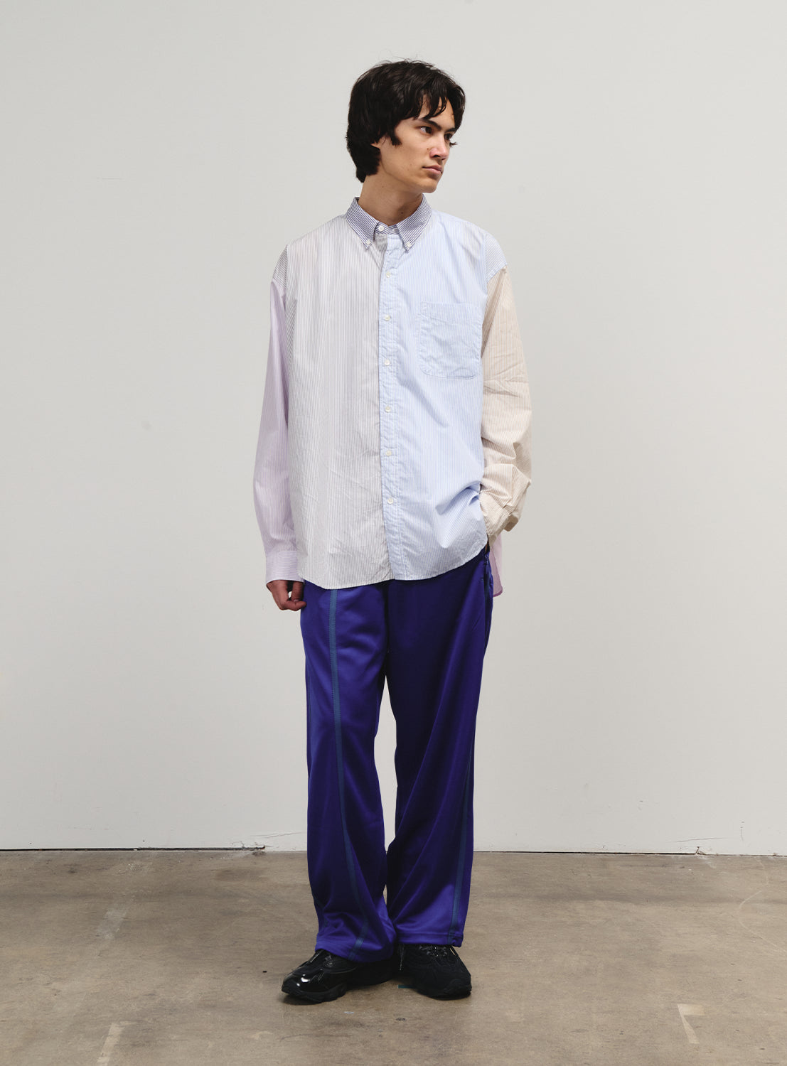 Front view of a model in blue track pants, embodying SSZ's understated design language.