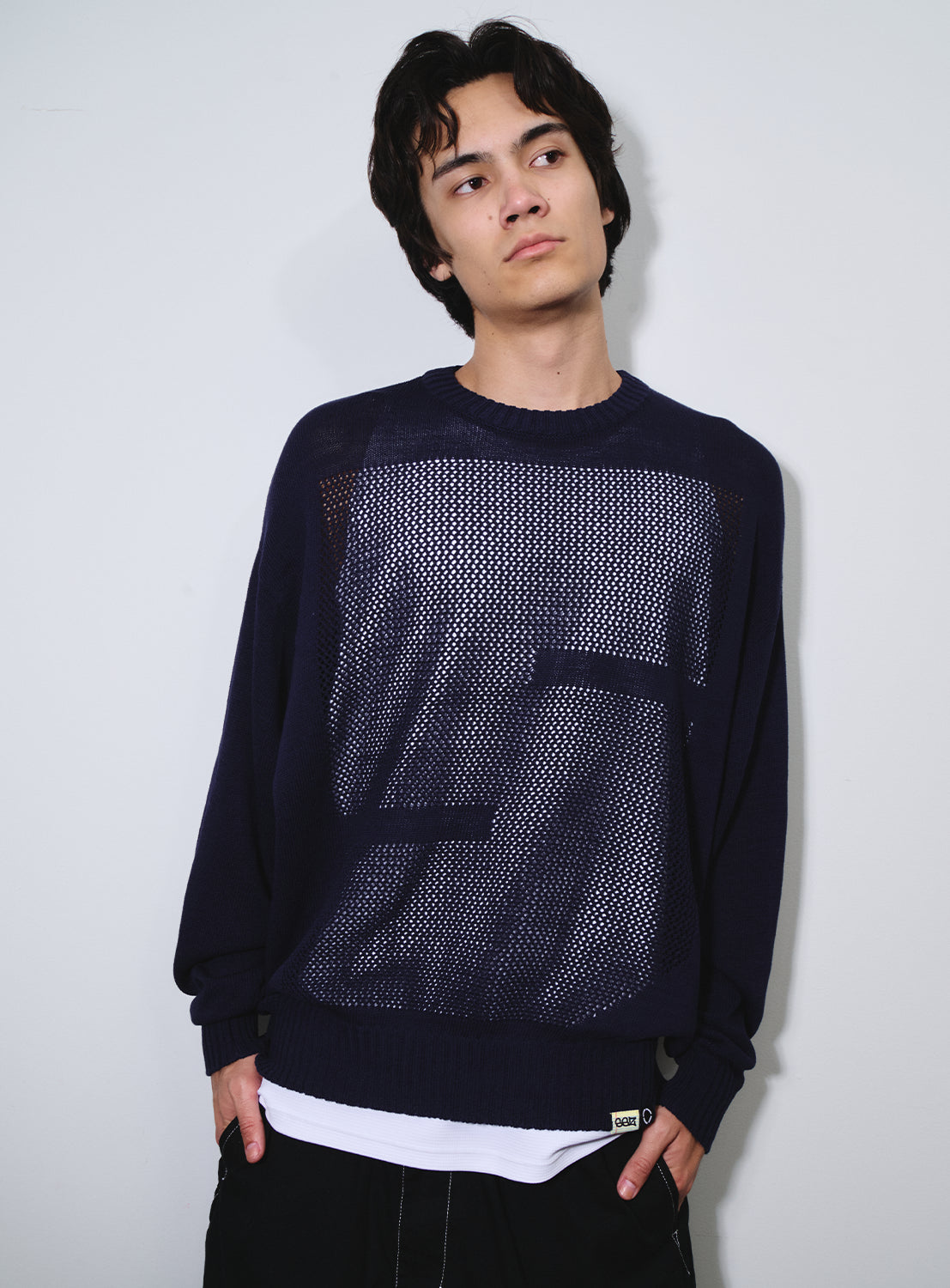 Model wearing a navy low-gauge knit sweater with a bold "S" detail, from the SSZ and PHINGERIN collaboration.