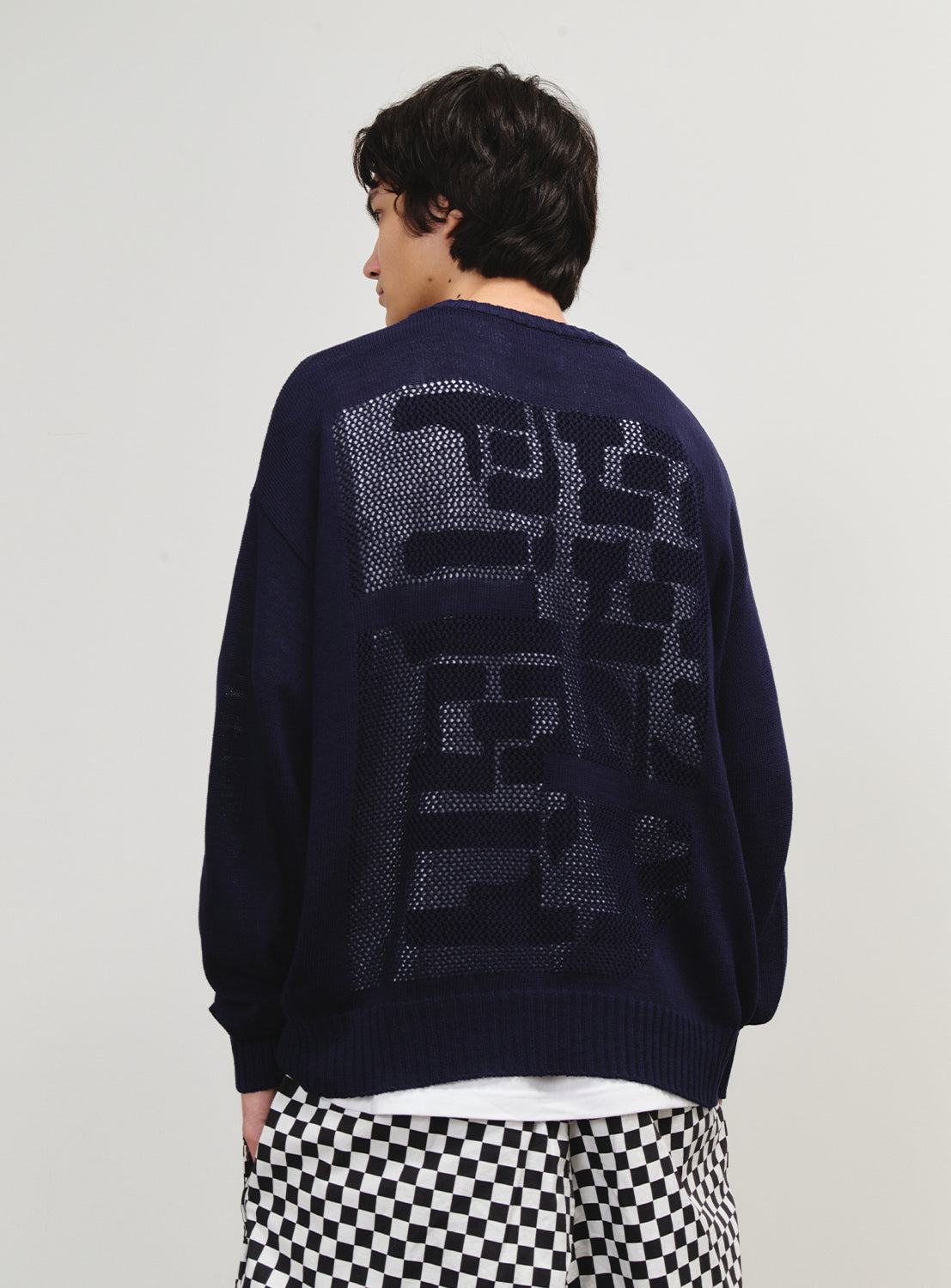 Back view of a model in the knit sweater, showcasing a bold "Z" detail and the "RELAX, LIGHT, and MODERN" theme.
