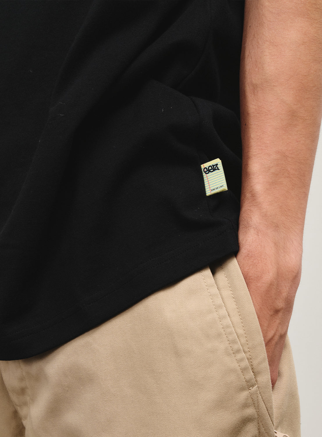 Close-up of a black T-shirt's hem, showing a small tag accent on the side.