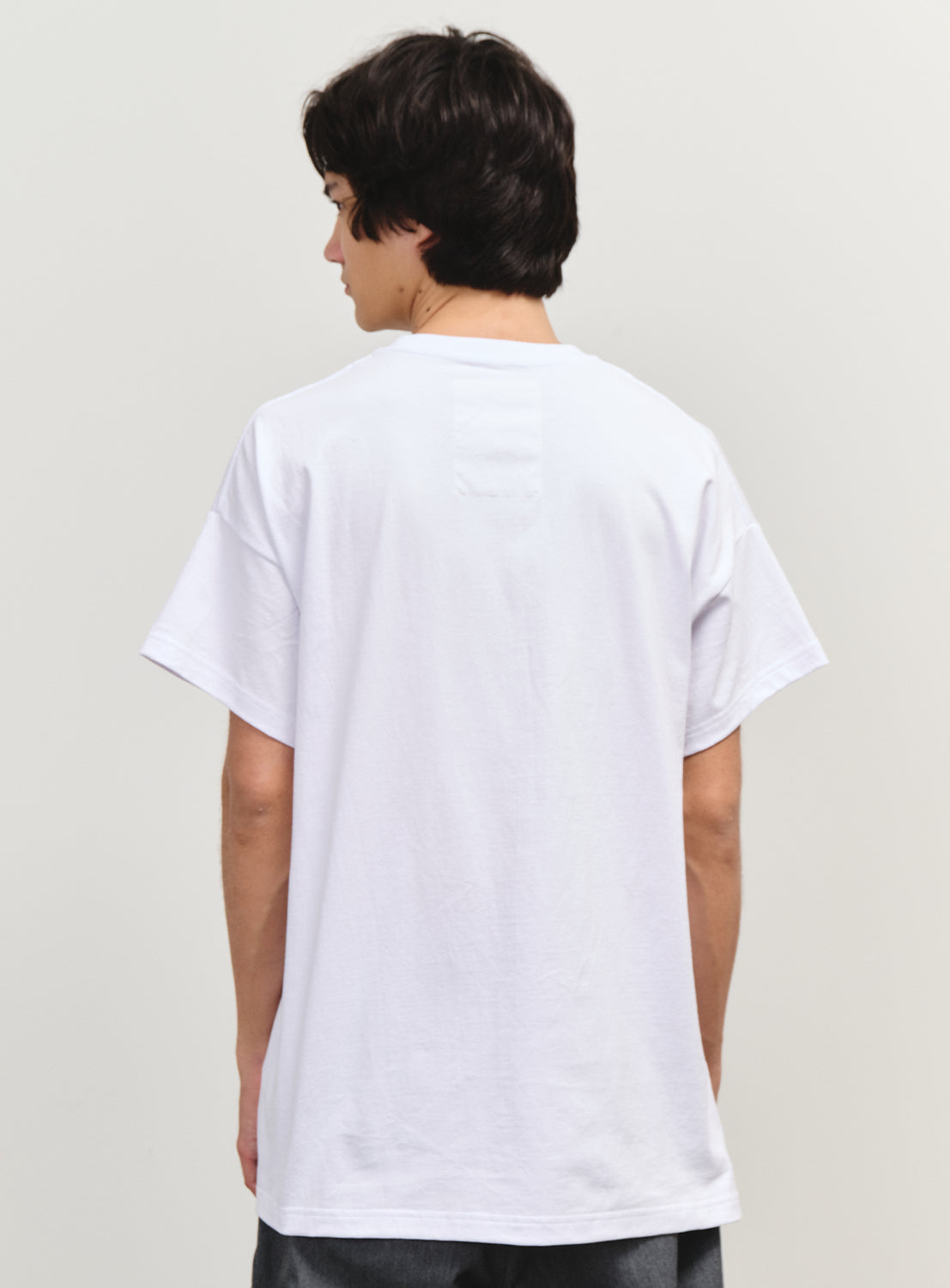 Back view of a model in a plain white T-shirt, showcasing a relaxed fit and clean silhouette.
