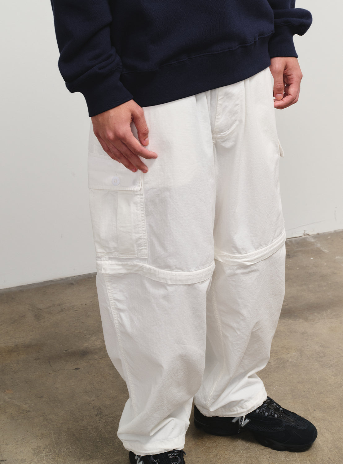 Close-up of white pants, showing the convertible zipper detail and their versatile design.