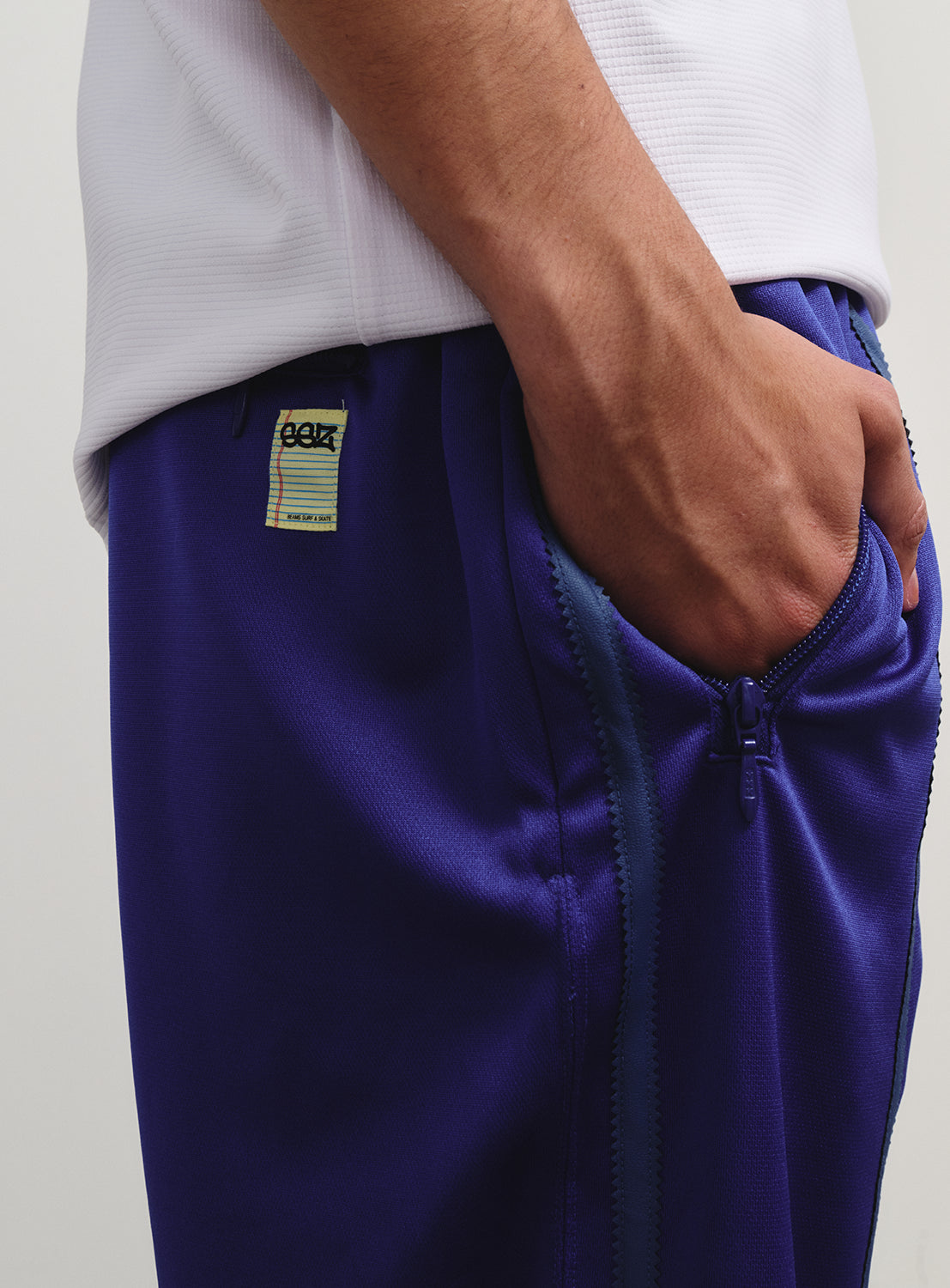 Close-up of the track pants' zippered front pocket, with a subtle SSZ logo underneath.