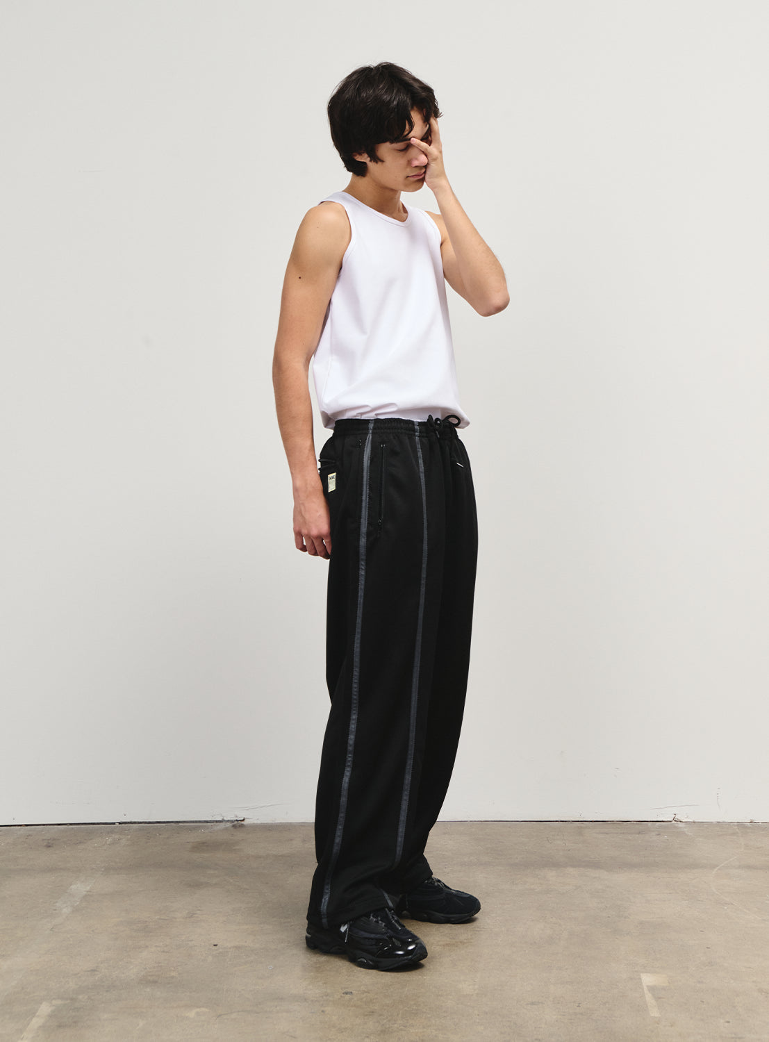 Side view of a model in black track pants, with an effortless balance of utility and style.