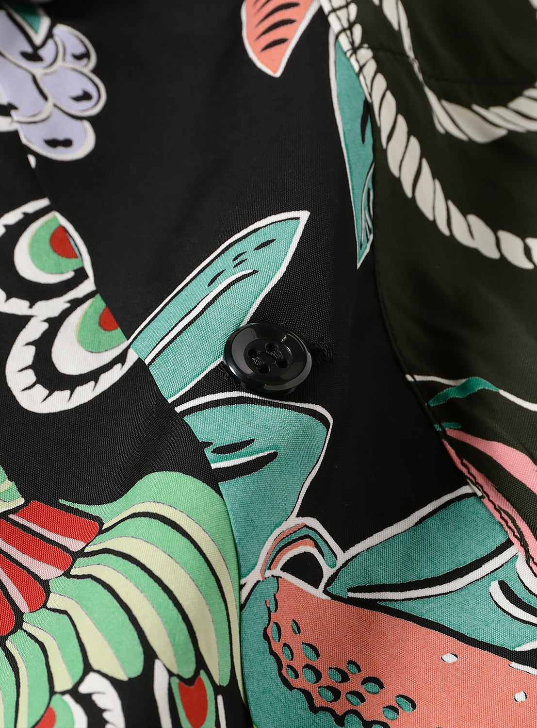 Close-up of a shirt with colorful abstract patterns and a black button.