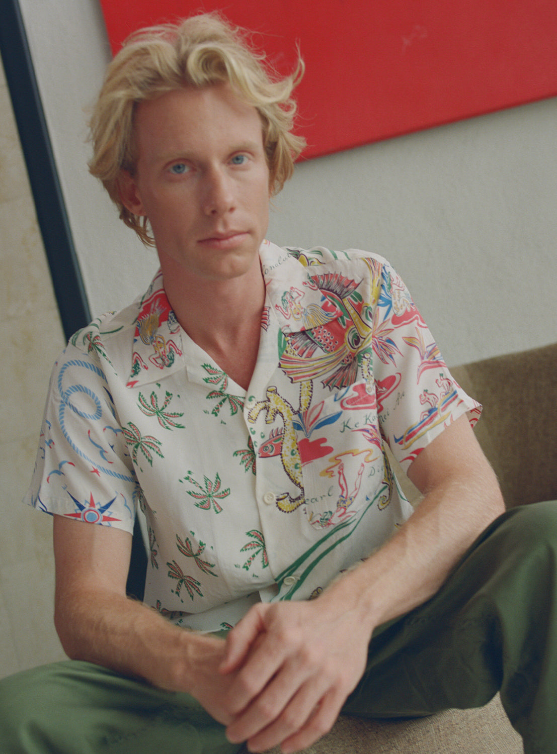 Model wearing colorful patterned white button down aloha shirt.