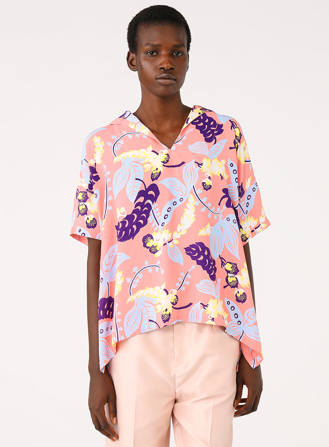 Full body shot of a model wearing a pink patterned shirt.