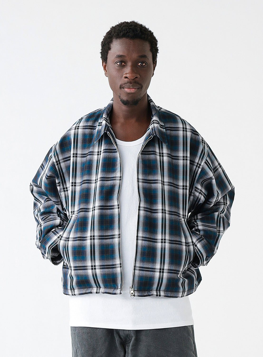 A model wearing a navy blue and white checkered blouson jacket with a collar and front pockets.