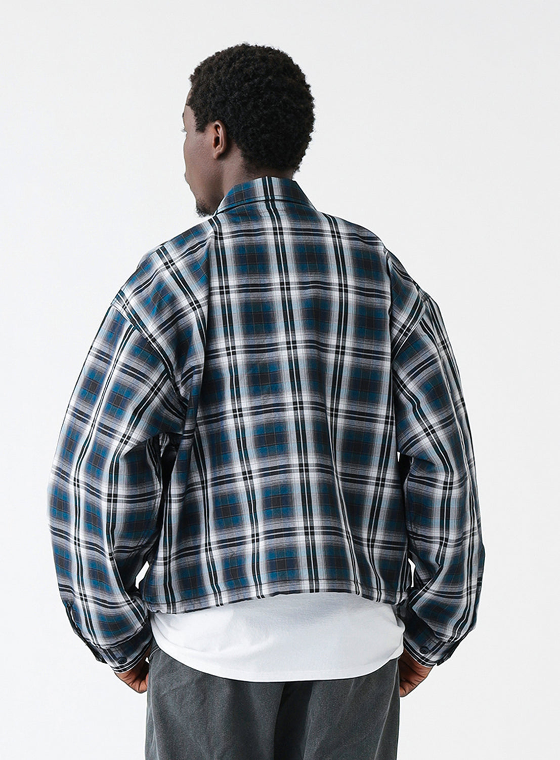 The back of a navy blue and white checkered blouson jacket with a collar and front pockets.