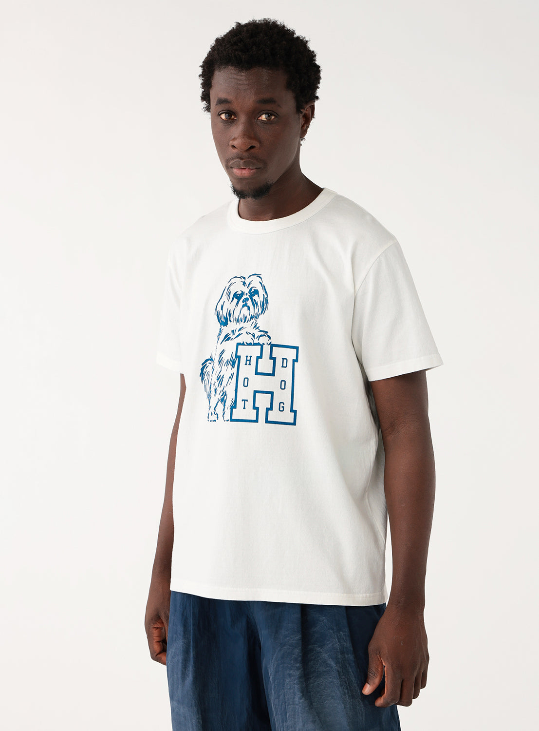 Model wearing a white t-shirt with a blue graphic and blue jeans, front view, displaying casual fit.