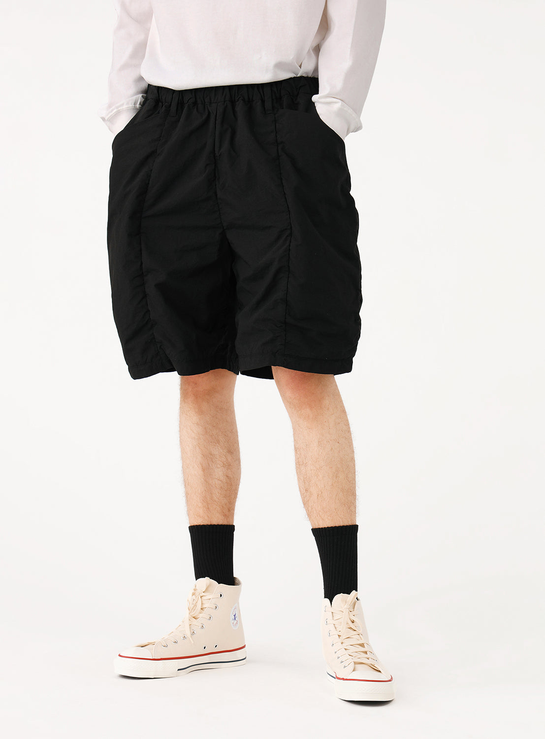Side view of a model in black PACKABLE shorts, showing an understated appearance that conceals their utility.