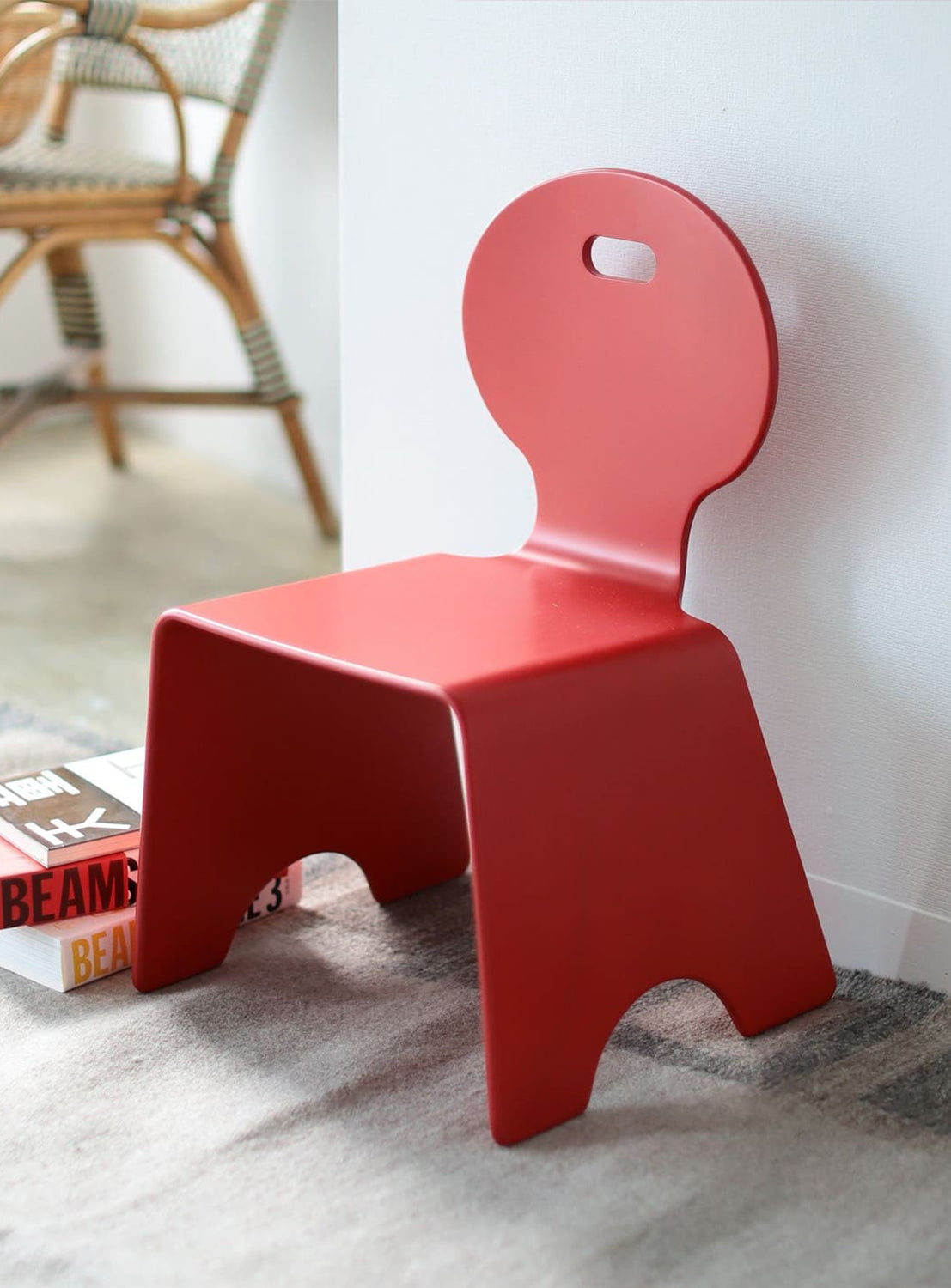 A red chair with a unique design, featuring a circular cut-out at the back and a flat seat.