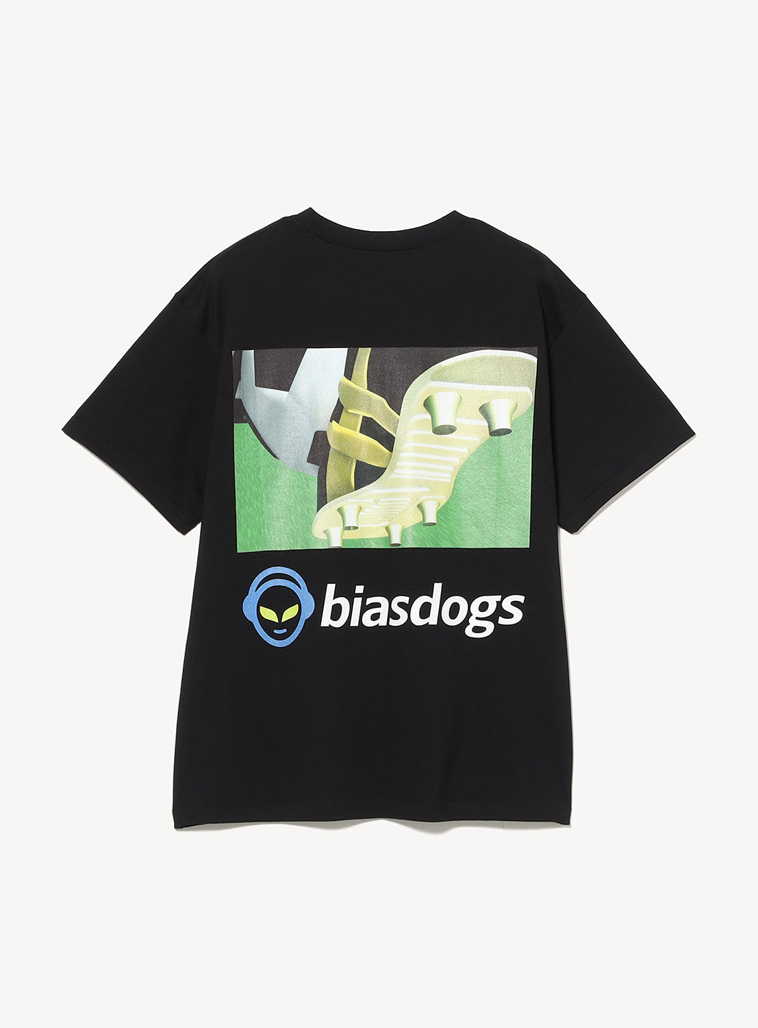 Introducing the Nappy Tee by BIAS DOGS: a black graphic T-shirt showcasing a bold, satirical soccer cleat artwork on grass, “biasdogs” printed underneath, and finished with a modern silhouette accented by a blue alien head logo on the lower left.