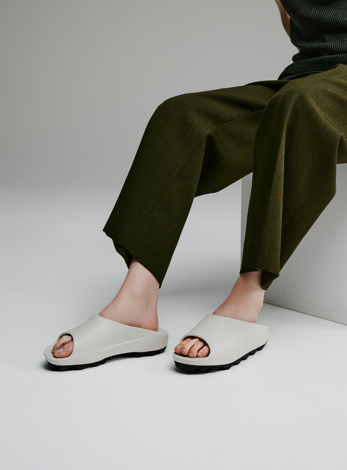 Styled shot showing the off-white slip-on sandals paired with casual trousers.