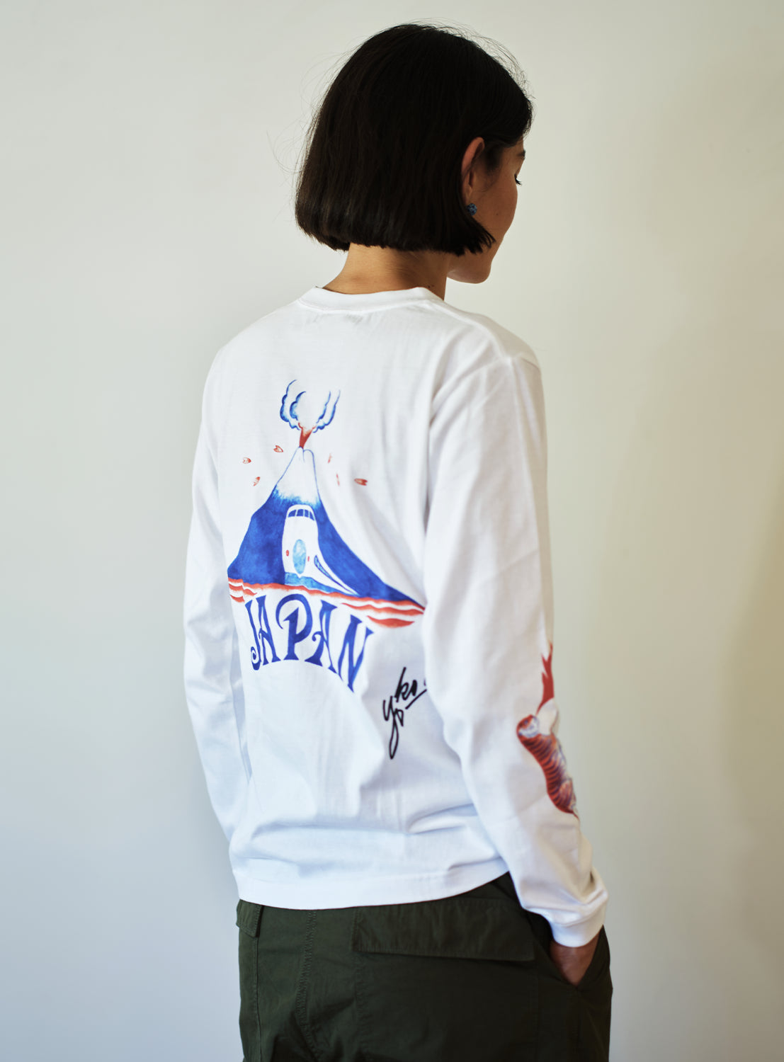 Model wearing a white long-sleeve shirt with a Mt. Fuji graphic design on the back.