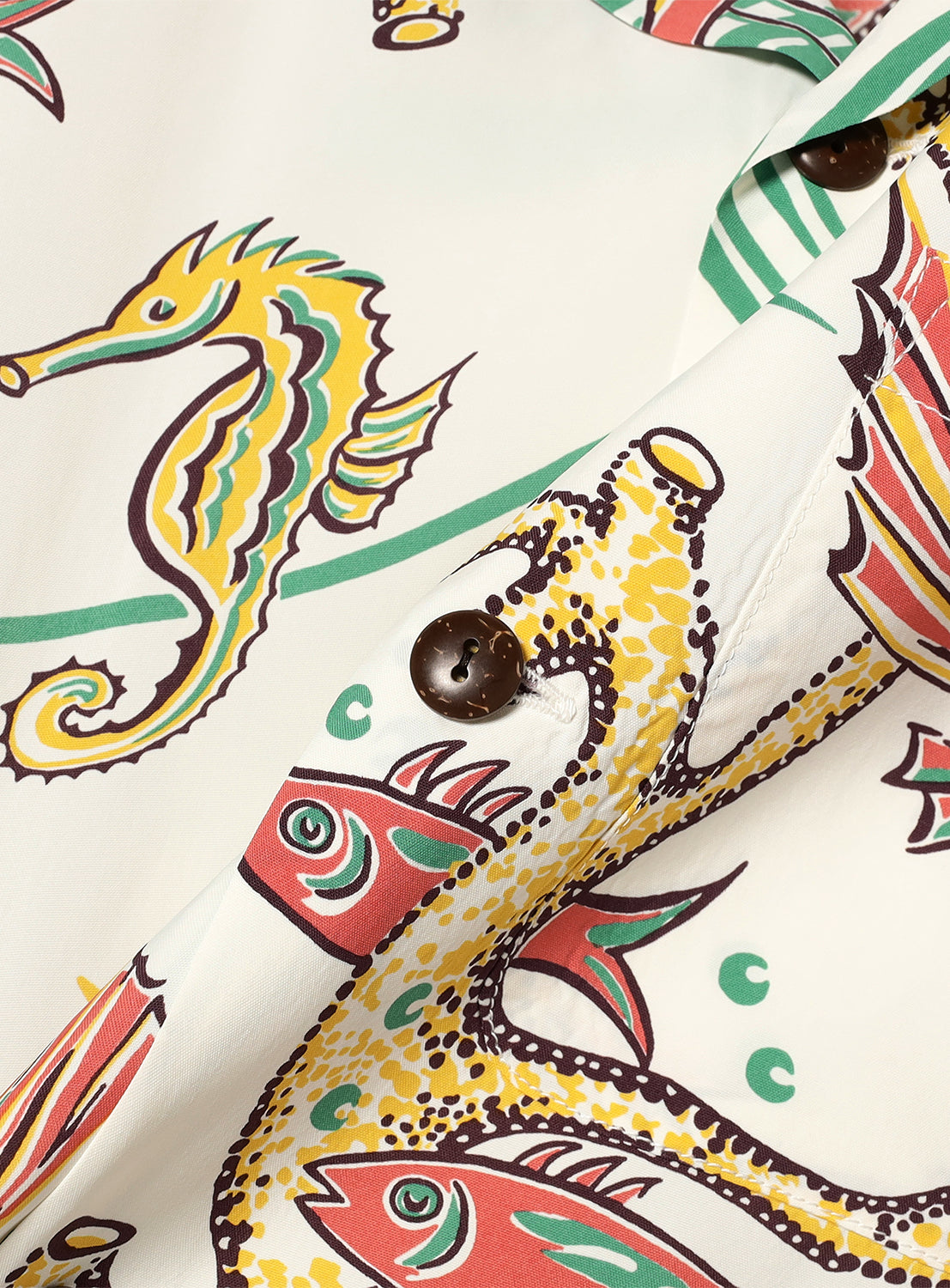 white patterned fabric, revealing the detailed seahorse and fish print and brown buttons. 
