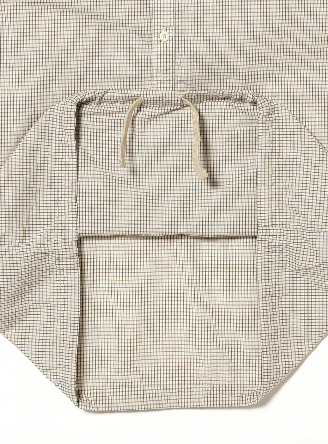 Close-up of a cream and brown small-checkered shirt, detailing the adjustable drawstring hem and fabric pattern.