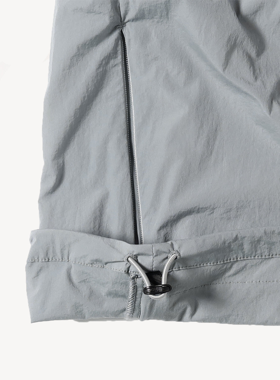  light grey jacket's hem, showing an adjustable drawstring and toggle detail.