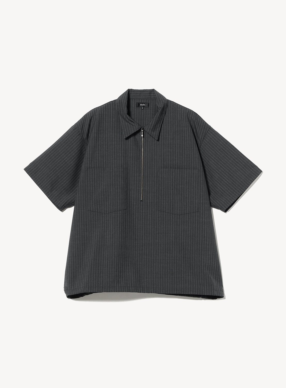 The BEAMS TW Wide Fit Half-Zip Shirt, shown laid flat on a white background, features a dark gray pinstriped design with short sleeves, a collar, front half-zip closure, and two chest pockets. It is crafted from a lightweight polyester-wool tropical fabric.