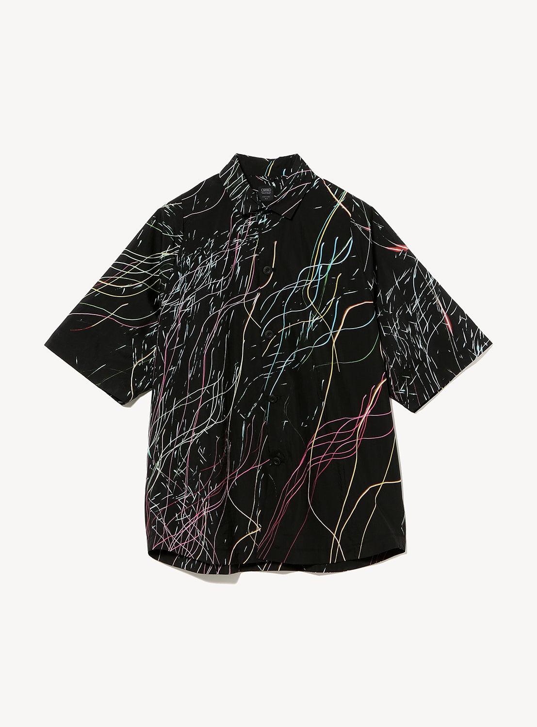 The TEATORA Short Sleeve Cartridge Shirt is a black, ultra-lightweight, wrinkle-resistant travel shirt featuring vibrant, paint-like streaks and lines in yellow, pink, blue, and white across the front and sleeves. The eye-catching design stands out against a plain white background.