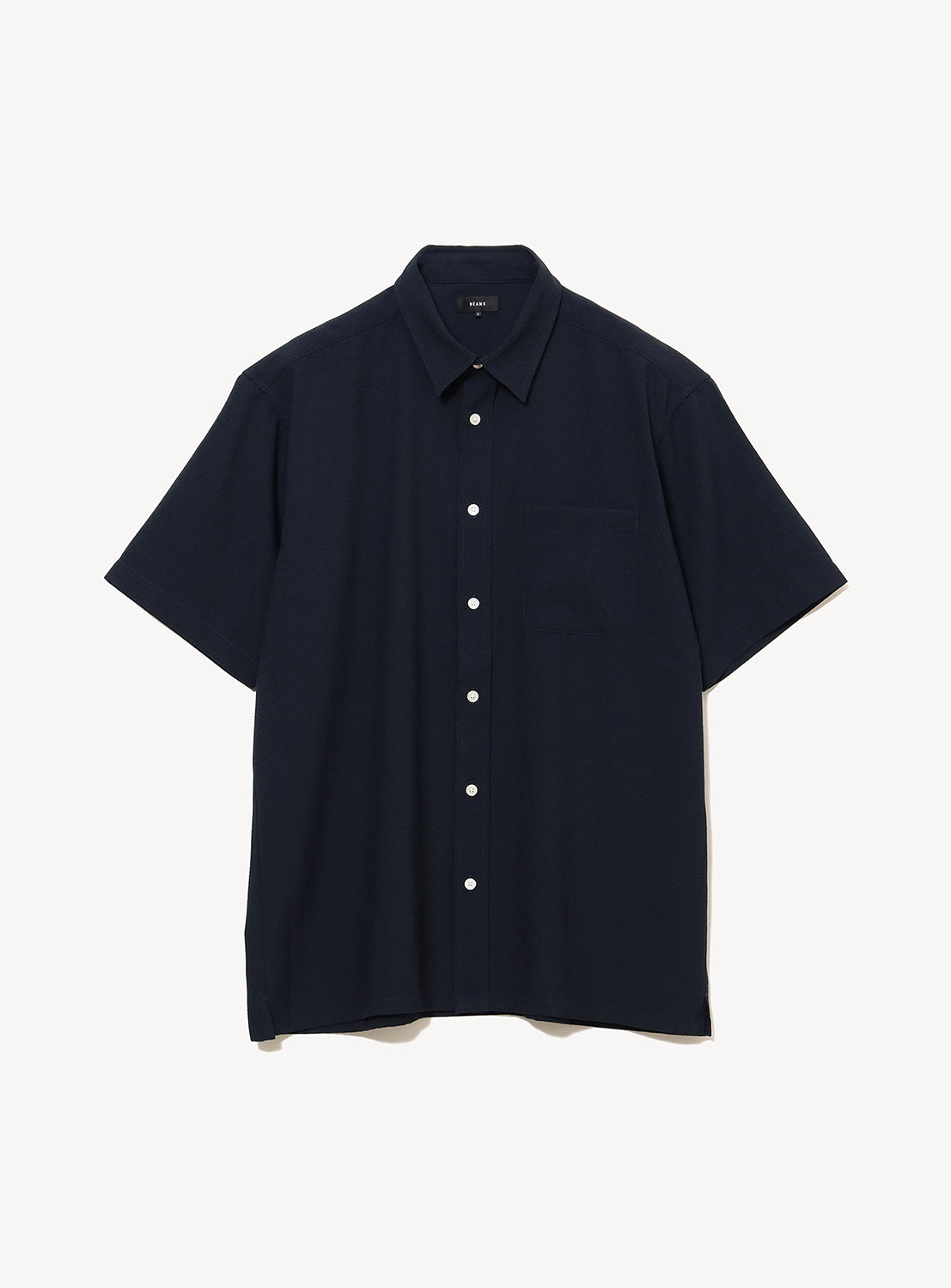 The BEAMS Stretch Quick-Dry Seersucker Relaxed Fit Shirt is a navy blue, short-sleeve, button-up shirt featuring a collar and chest pocket, made from lightweight, wrinkle-resistant fabric. It is displayed laid flat on a white background.
