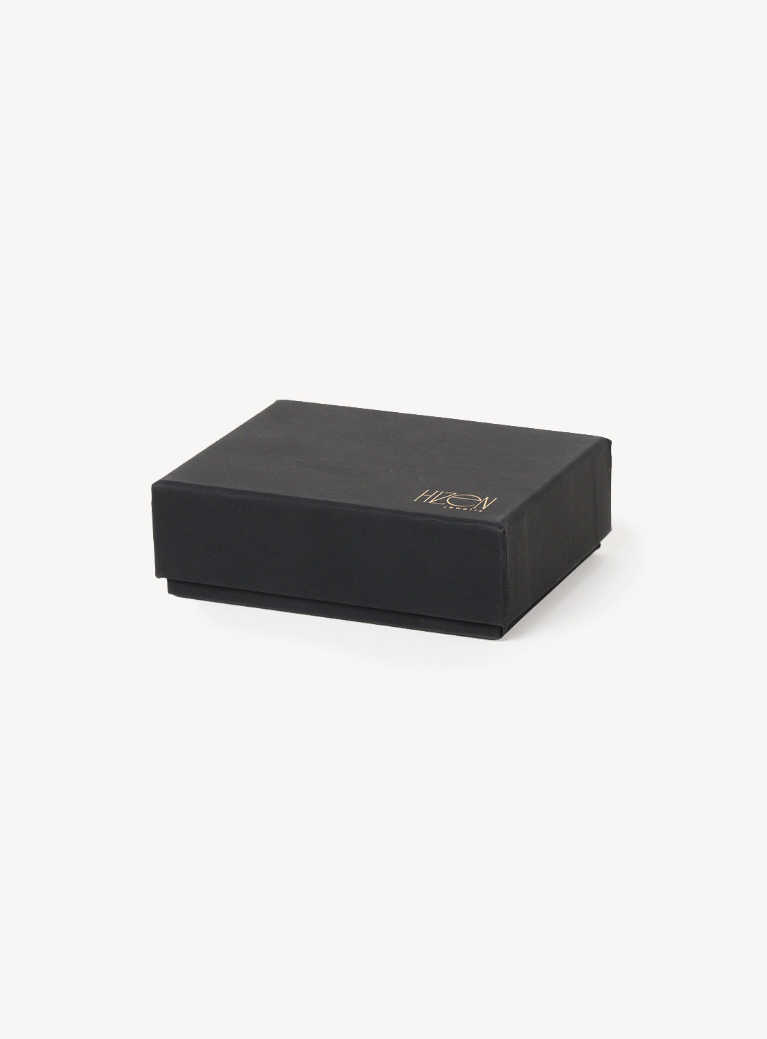 A closed, rectangular black box bearing the Hizen Jewelry gold logo on its lid is set against a white background—an elegant presentation that beautifully showcases the meticulous attention to detail behind their Arita Ware Motif & Baroque Pearl Earrings, inspired by Japanese craftsmanship.