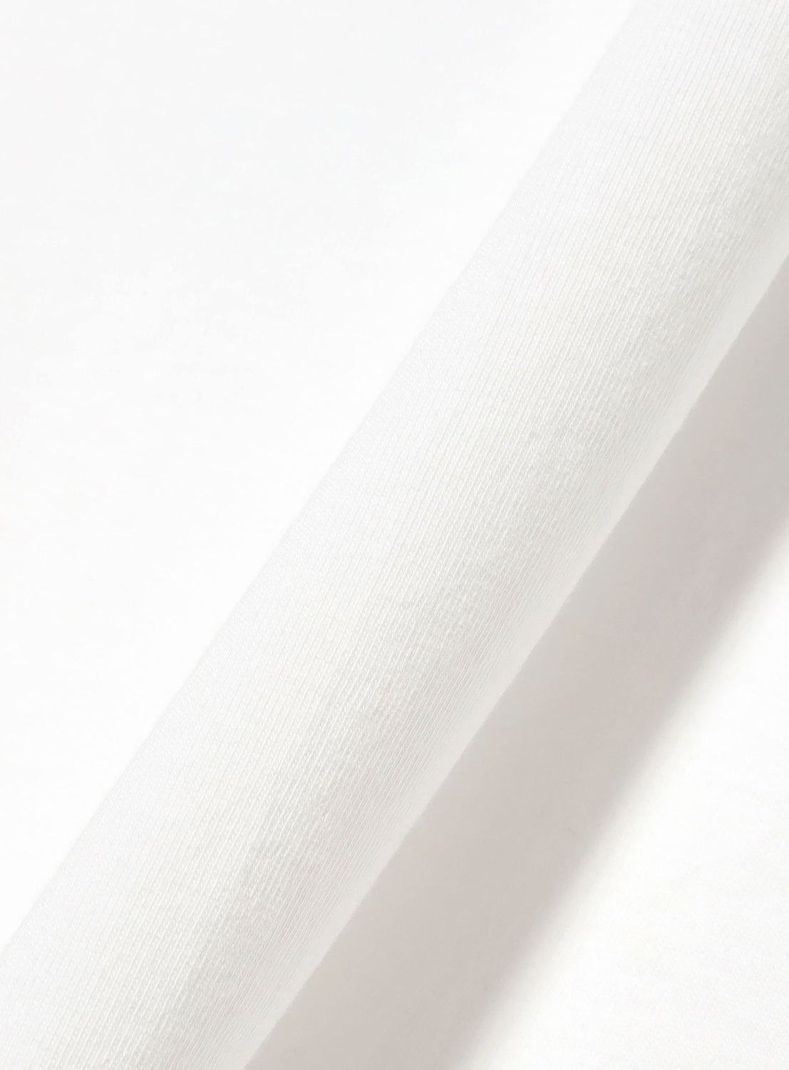 A close-up view of a white roll of fabric on a light background, showcasing its smooth texture and soft appearance—ideal for creating the relaxed wide-fit Onna Fishing Theme Graphic T-Shirt by Chaos Fishing Club or incorporating fishing-inspired artwork.