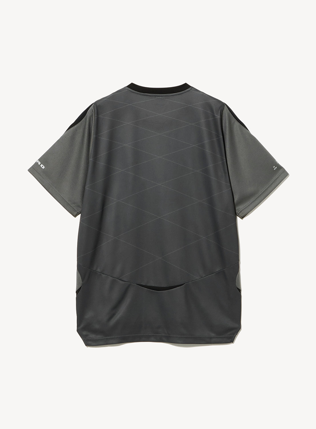 A short-sleeved, dark gray BAL × UMBRO Soccer Jersey is laid flat to reveal the back. This relaxed-fit shirt features subtle geometric patterns, complemented by light gray panels on the sides and sleeves. Made from moisture-wicking polyester, this BAL collaboration with UMBRO takes inspiration from retro football design, blending classic and modern athletic style.
