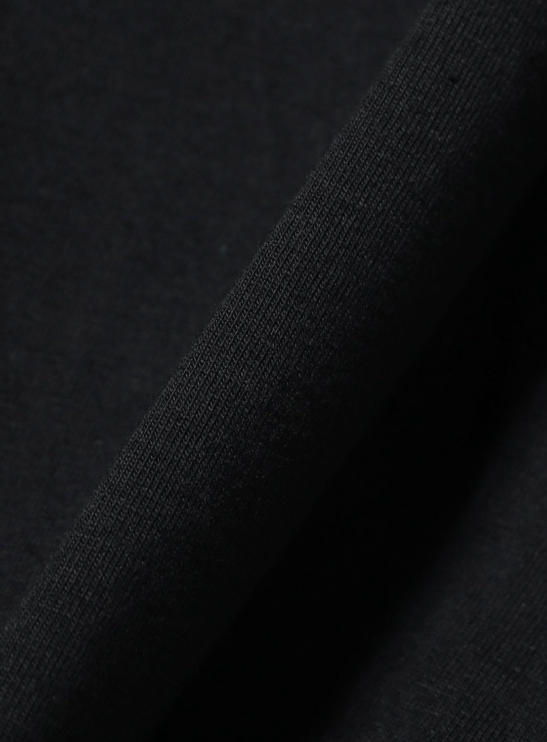 A close-up view of a folded piece of black fabric from the Chaos Fishing Club Short Sleeve Onna T-Shirt, highlighting its smooth texture and fine weave.