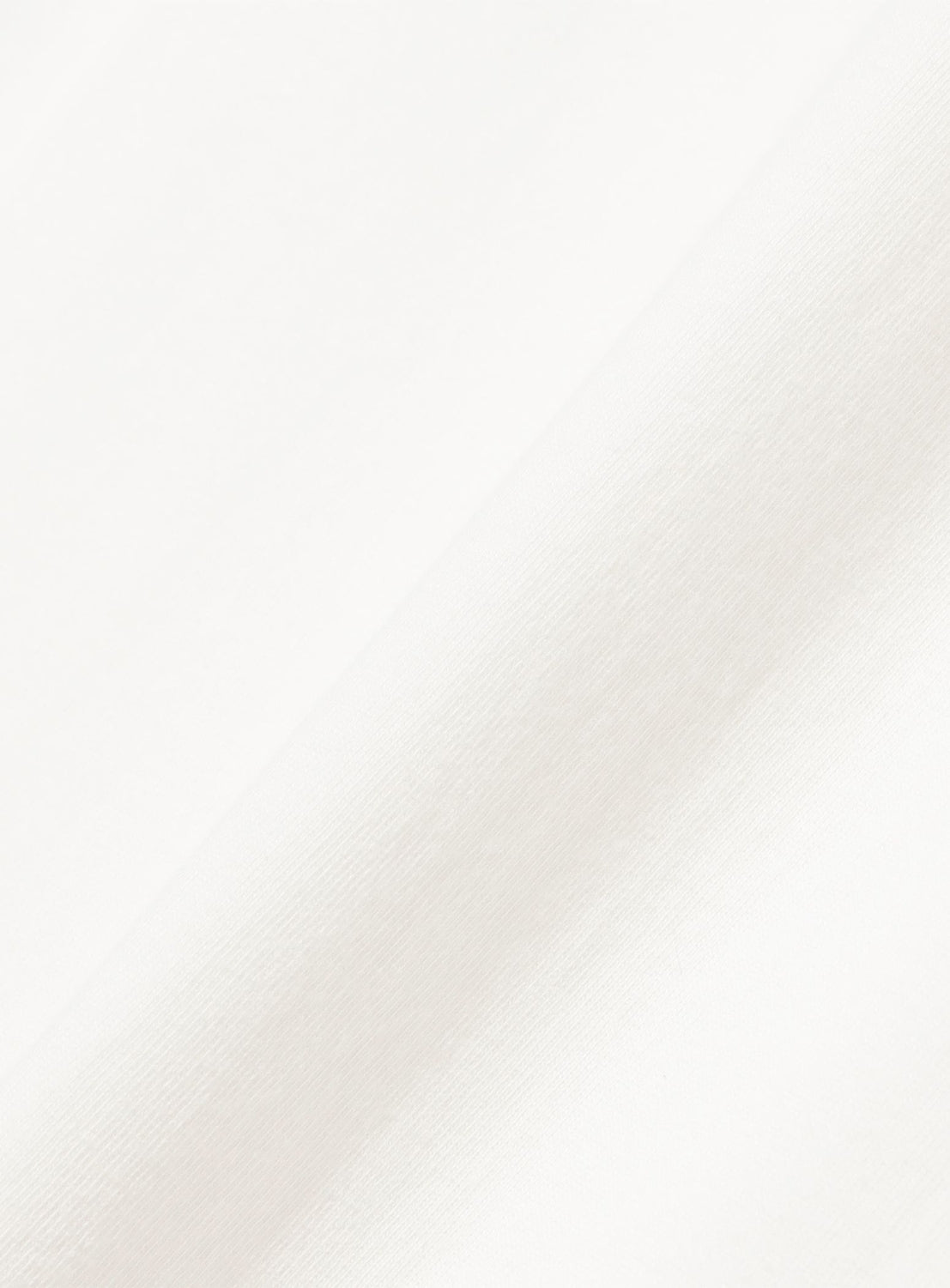 Close-up view of soft, white fabric with a slight diagonal crease, similar to the smooth weave on a Chaos Fishing Club Tairyo Short Sleeve T-Shirt, with gentle lighting highlighting its subtle folds.