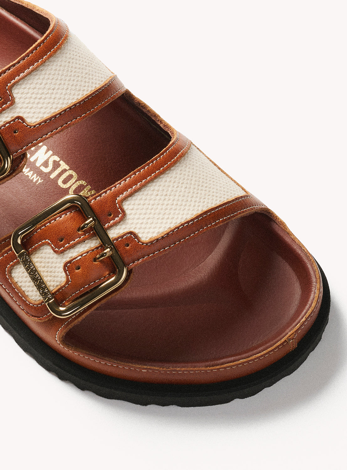 Brown sandal with a gold buckle on a white background