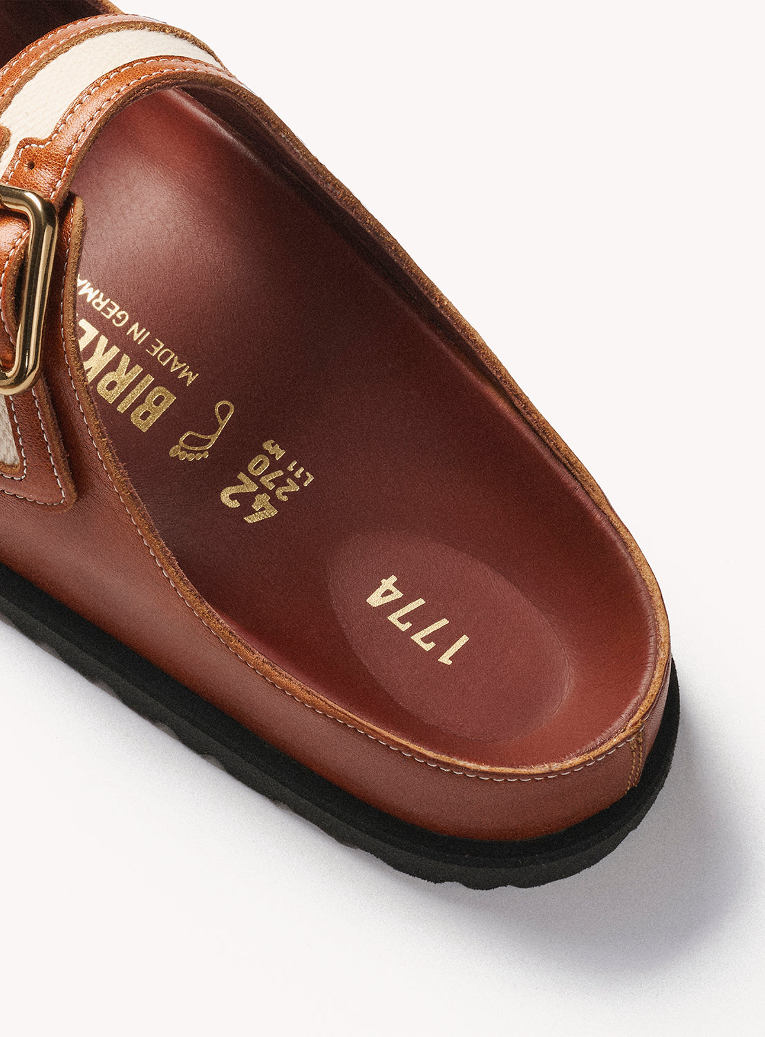 Brown leather sandal with gold buckle on a white background