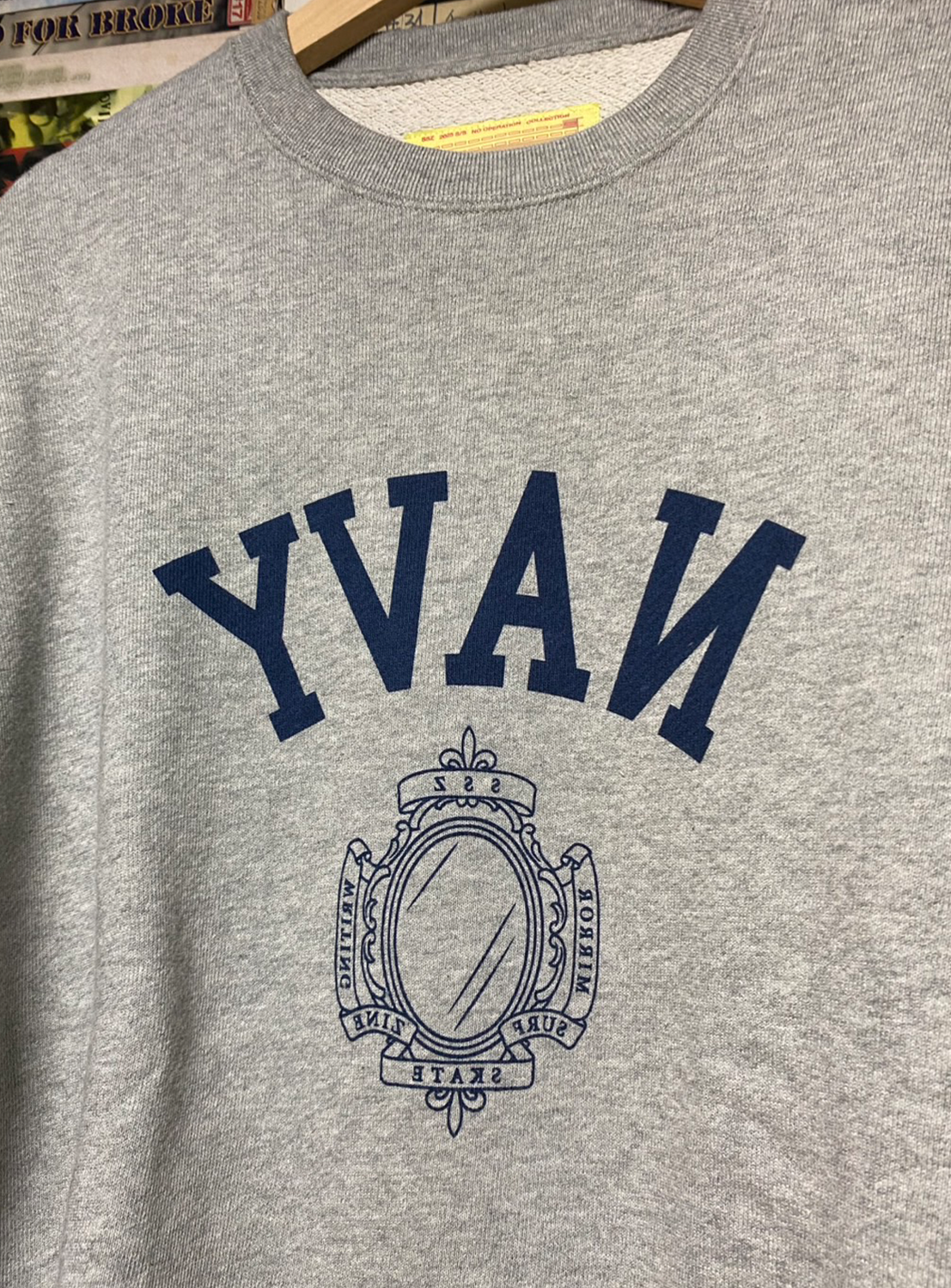 Close-up of a grey sweatshirt, showing the "YVAN" graphic with a mirror-image perspective and a crest design.