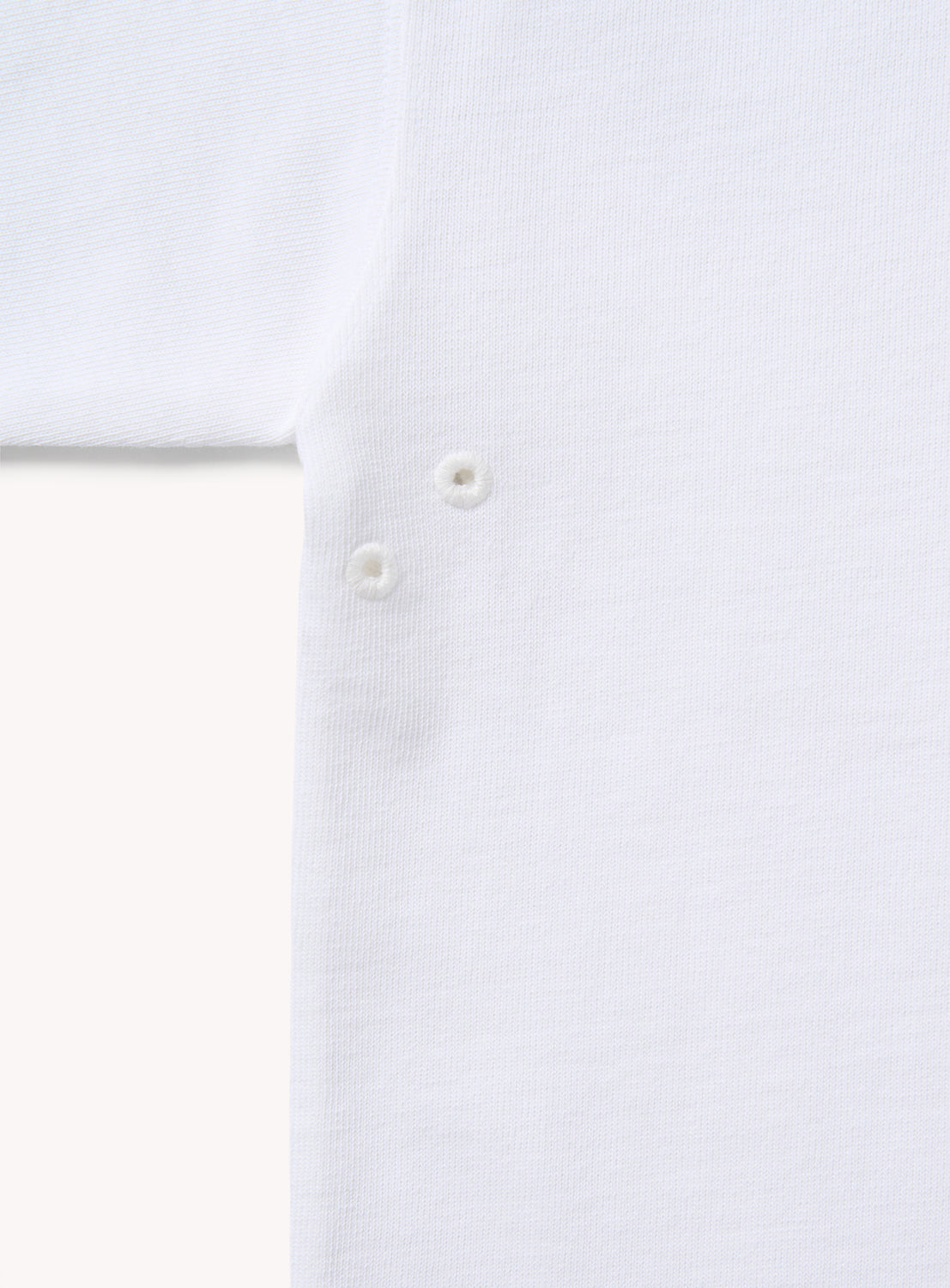 Close-up of BEAMS the A - Suvin Turi T-Shirt in white, highlighting its premium fabric, part of a sleeve, and three small metal snap buttons arranged vertically along the seam.