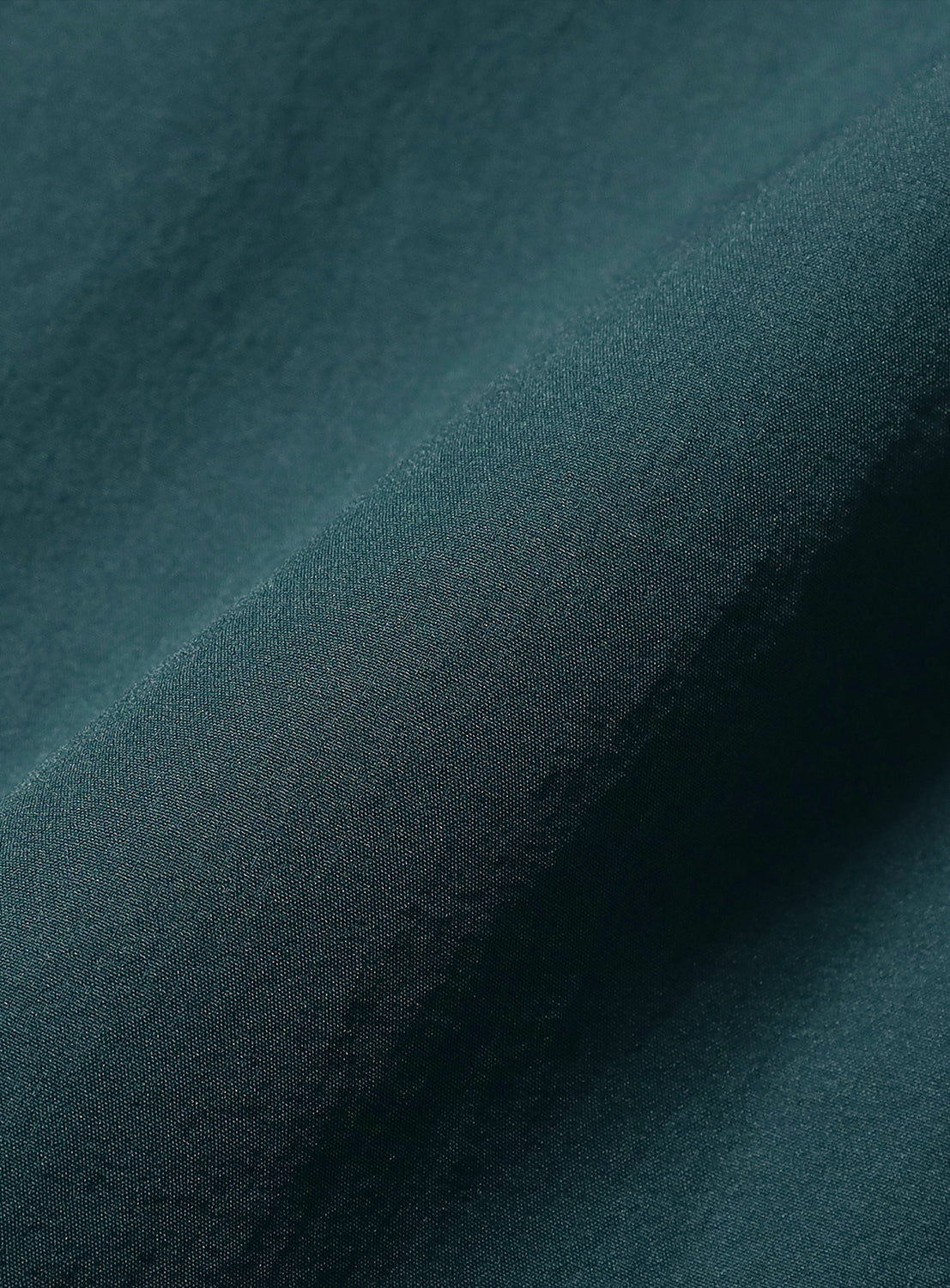 dark blue-green material, highlighting the fabric's quality and soft drape.