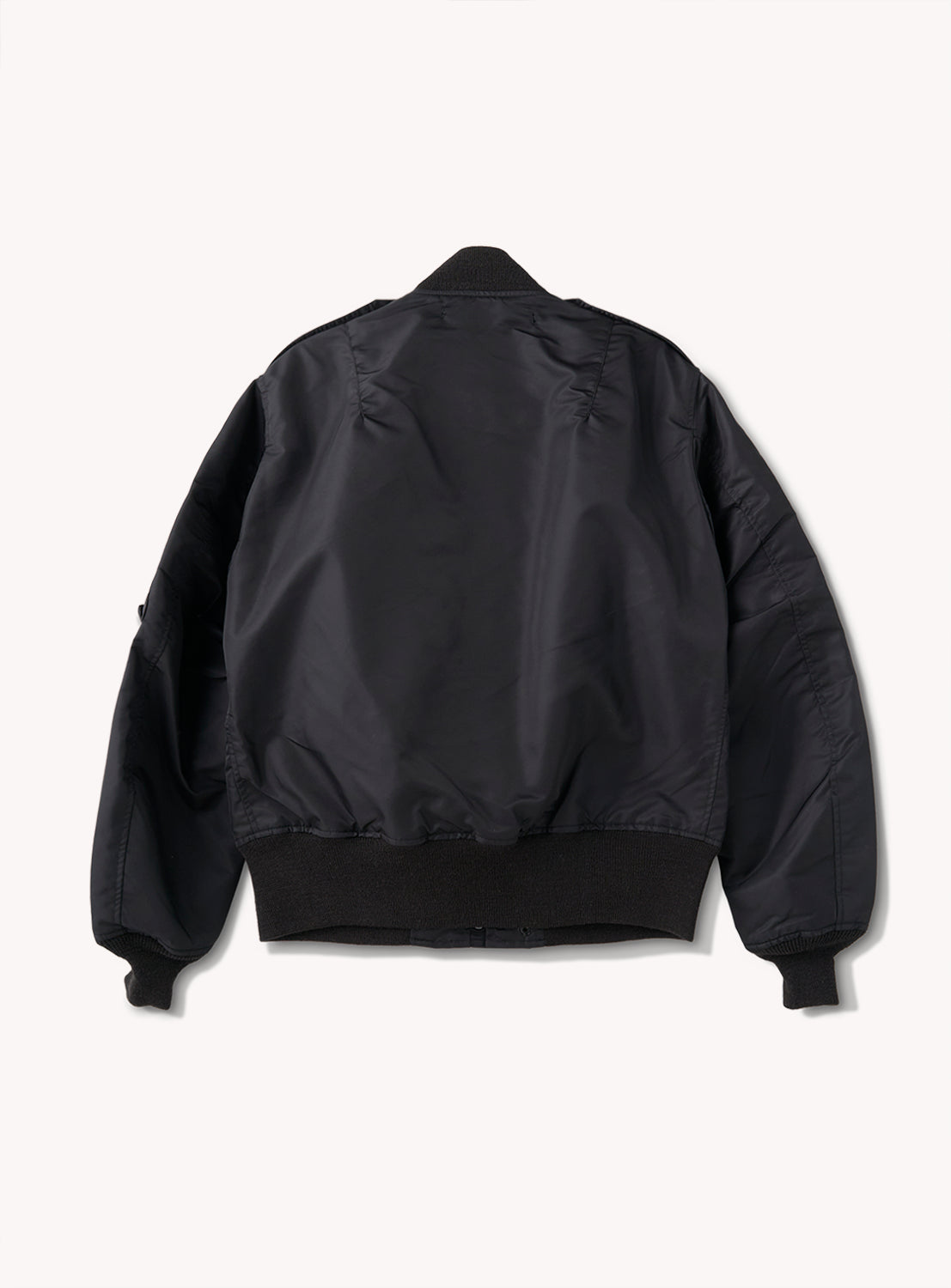 A BUZZ RICKSON’s William Gibson Collection L-2B black bomber jacket, made in Japan, is displayed from the back with ribbed cuffs, waistband, and collar on a plain white background.