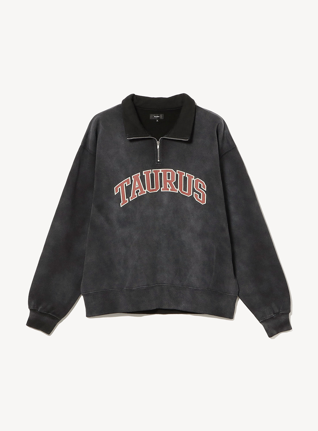 BEAMS Faded Souvenir Half Zip Pullover: a black half-zip sweatshirt in a cropped silhouette with a collar and the word TAURUS in arched, varsity-style lettering across the chest.