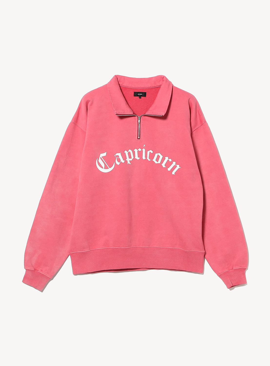 Faded Souvenir Half Zip Pullover in pink, a cropped half-zip sweatshirt with a collar and Capricorn in white gothic lettering across the chest.