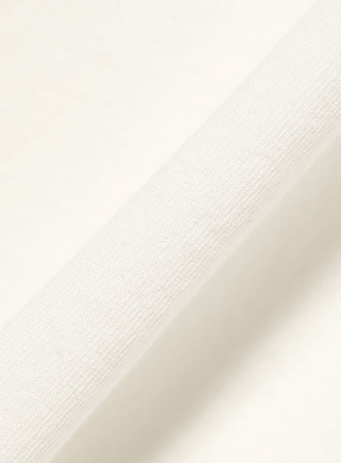 A close-up of the F-LAGSTUF-F Box Logo T-Shirt's heavyweight cotton jersey fabric, displayed diagonally across the image to emphasize its woven pattern and soft appearance.