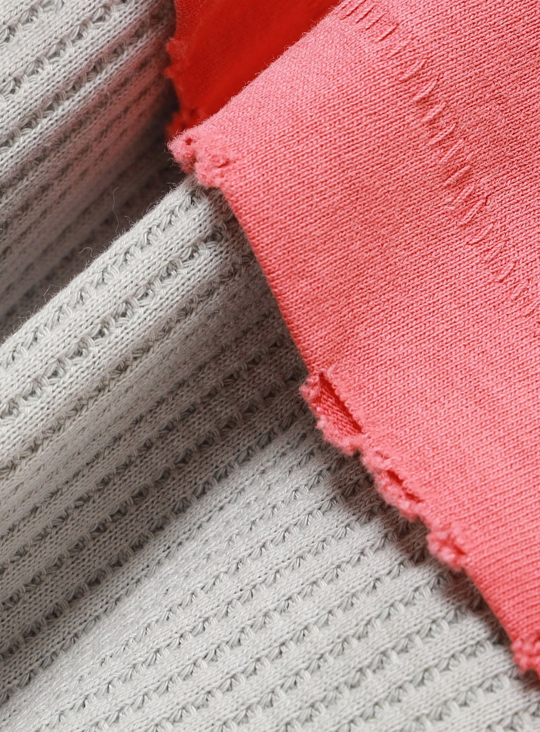 Close-up of a pink distressed cotton jersey edge with a frayed, raw hem layered over a textured gray thermal long sleeve on the Vintage Layered Fade Long-Sleeve T-Shirt by BEAMS.