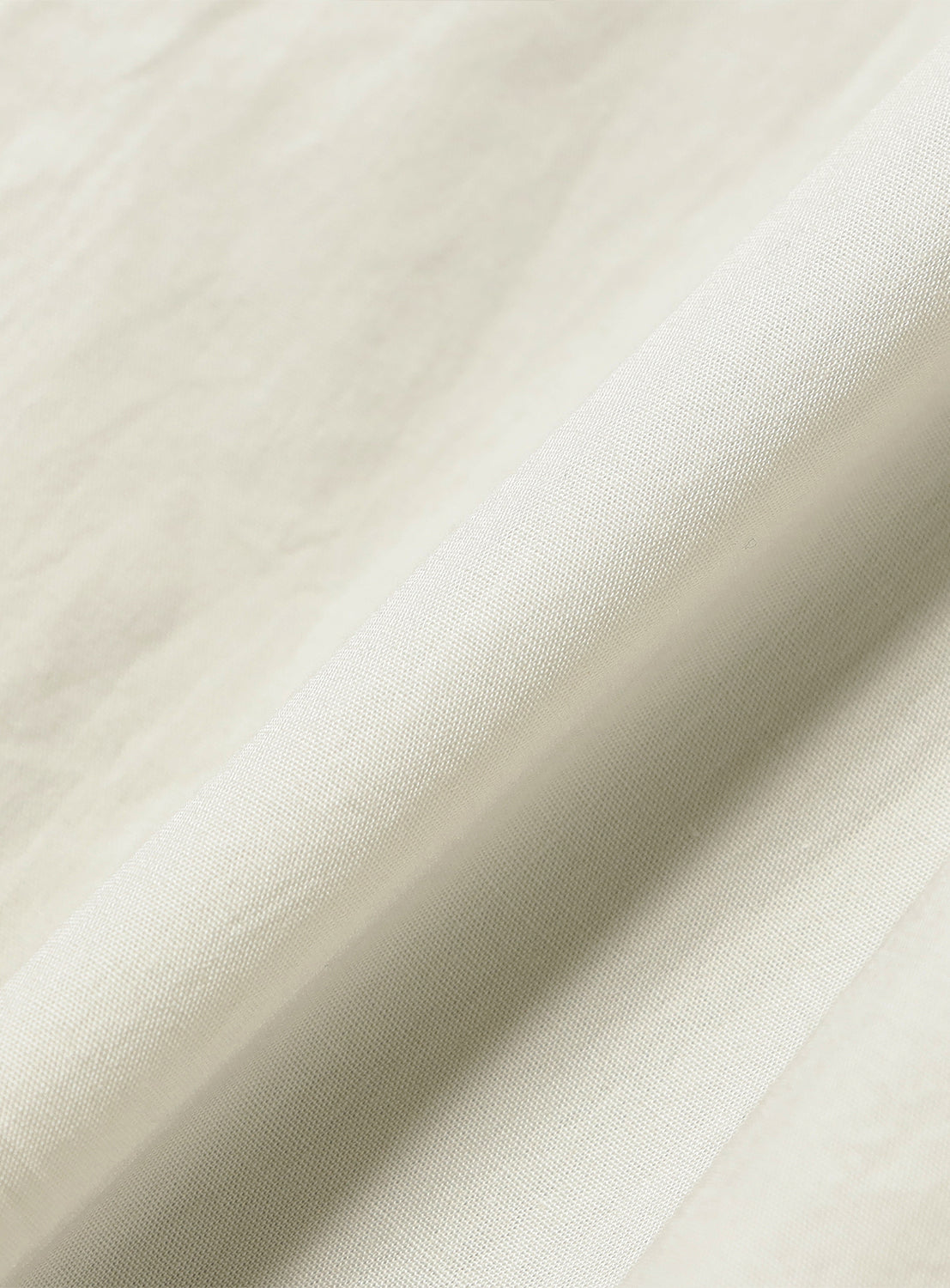 Close-up of cream 100% cotton fabric, detailing the soft texture and natural weave of the jumpsuit.