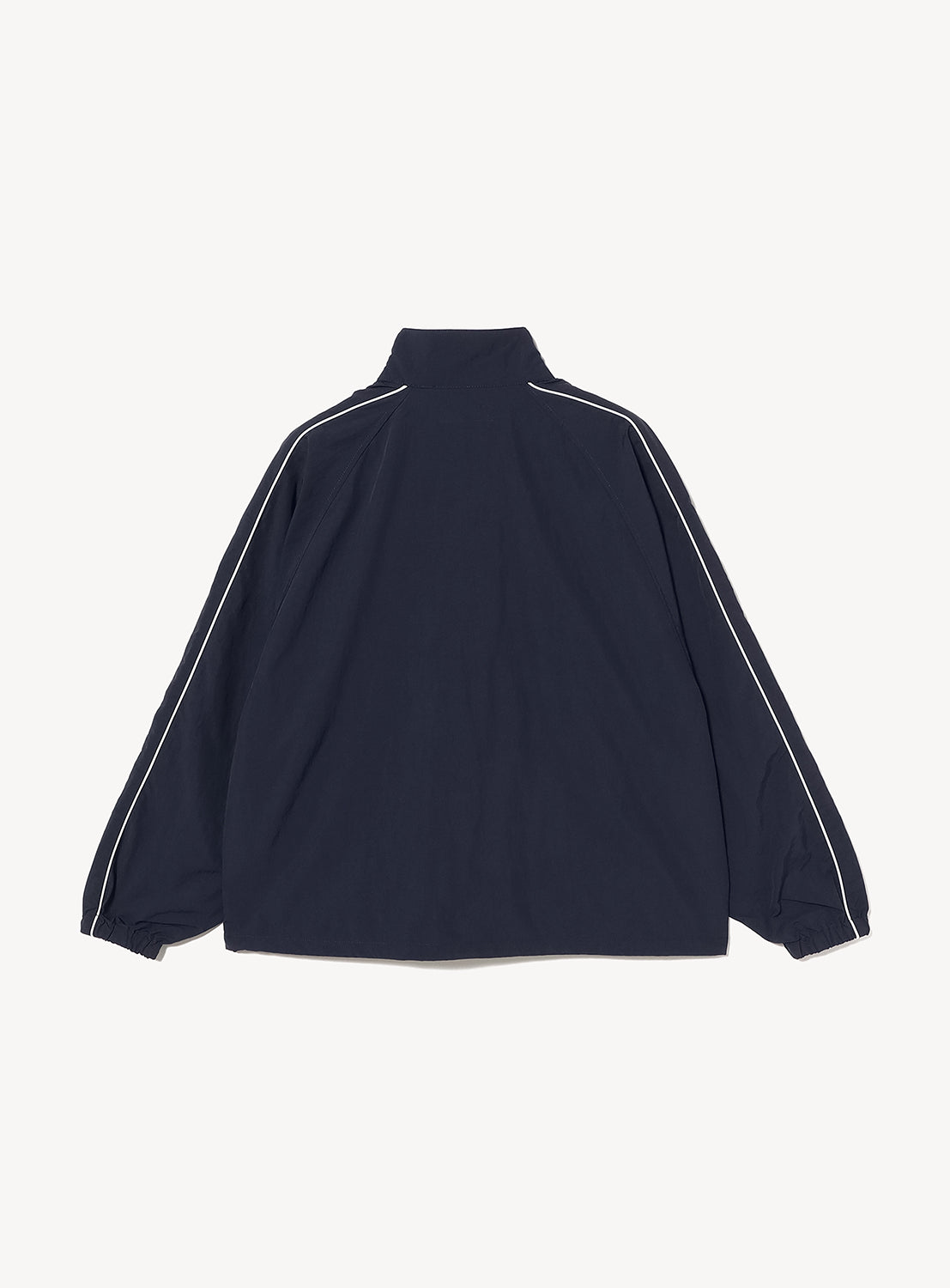 BEAMS T Tyrrell Winston - Anorak Jacket in navy blue, featuring a stand collar, white piping along the sleeves, and elastic cuffs. Drawing inspiration from vintage training wear, this jacket is presented from the back against a plain white background.