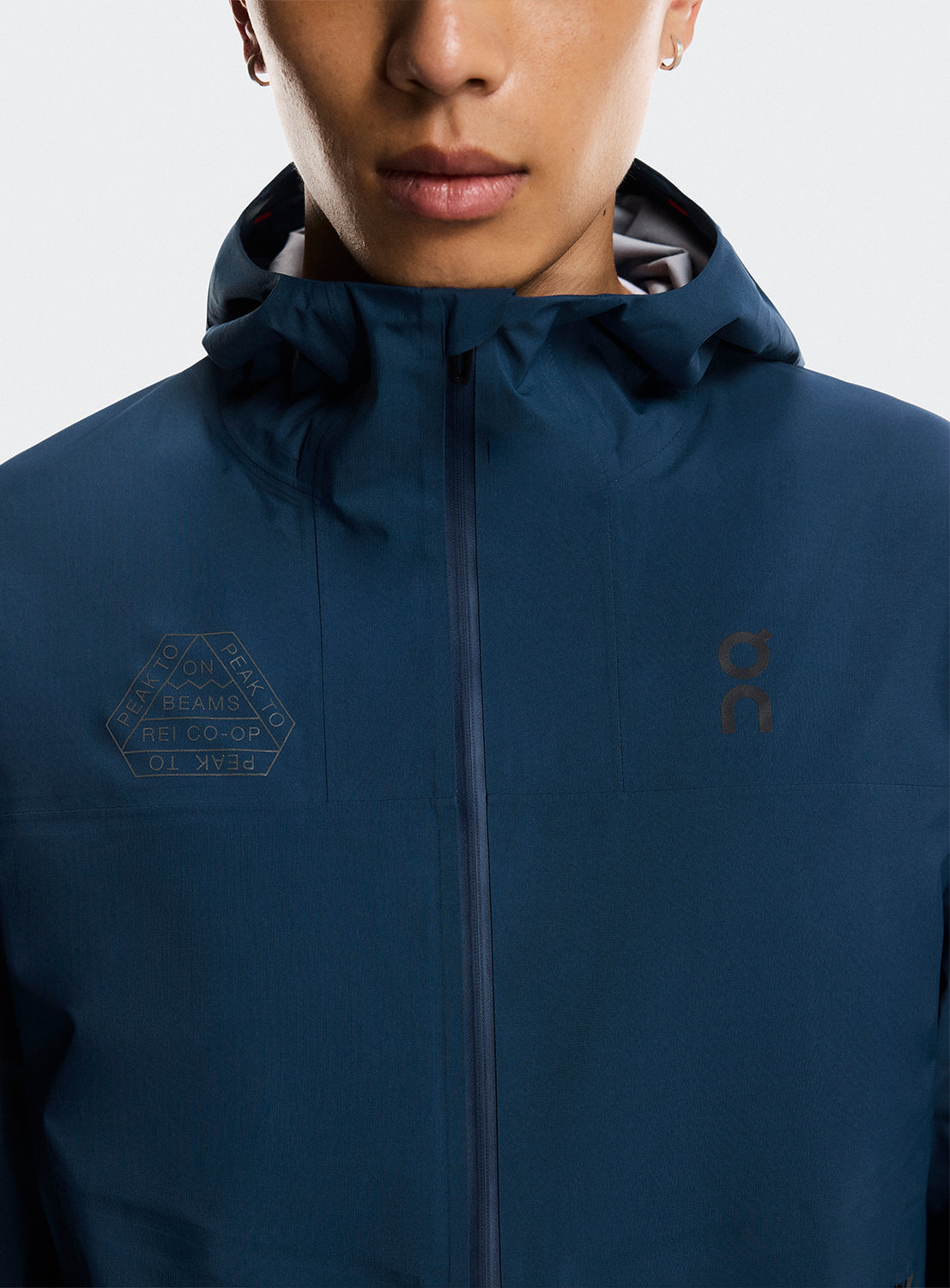 Close up of the zipper jacket detail with the ON Running logo detail and BEAMS X REI CO-OP logo. 