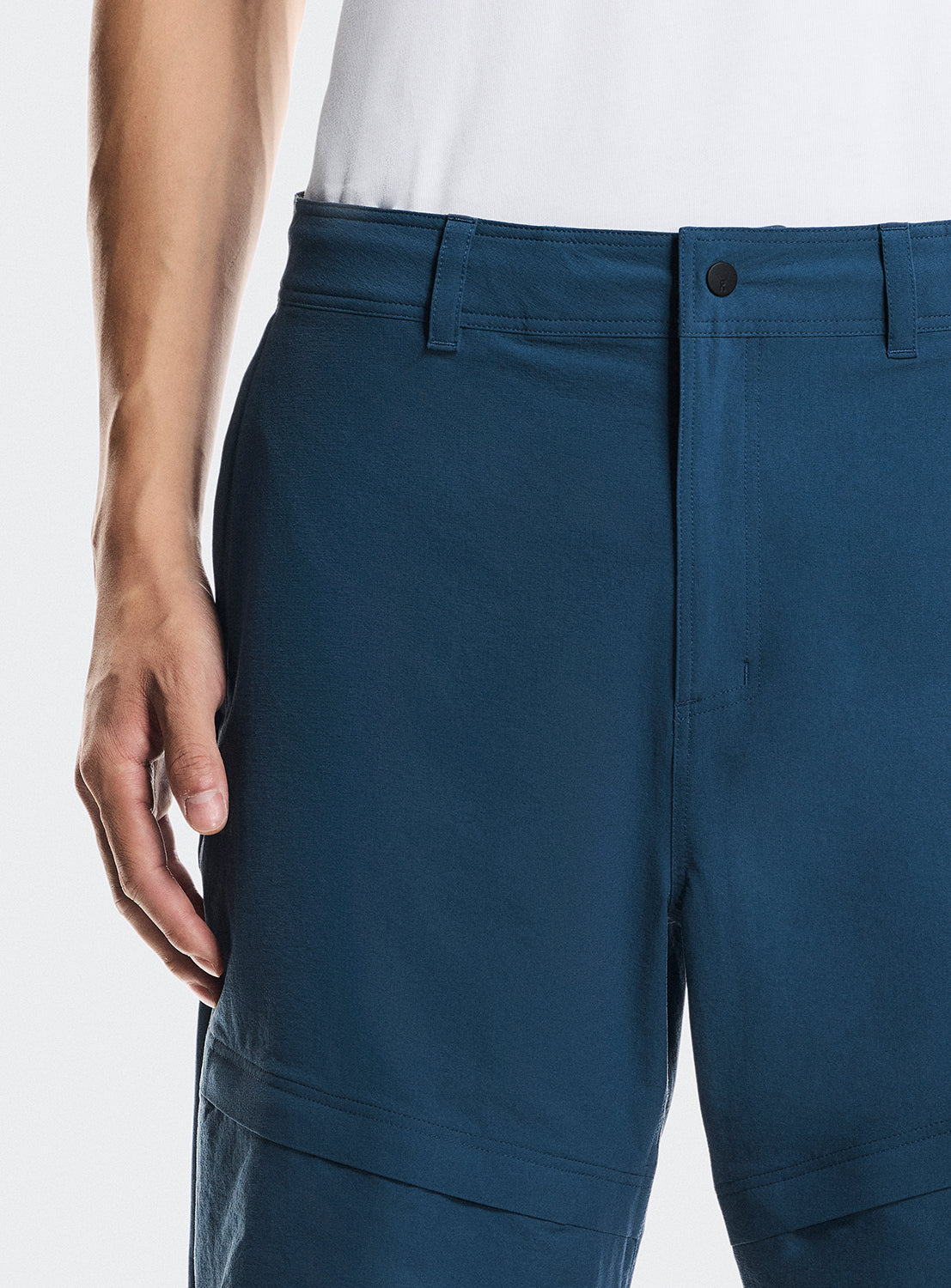 Close up of the blue trek pants highlighting the button details and belt loops. 