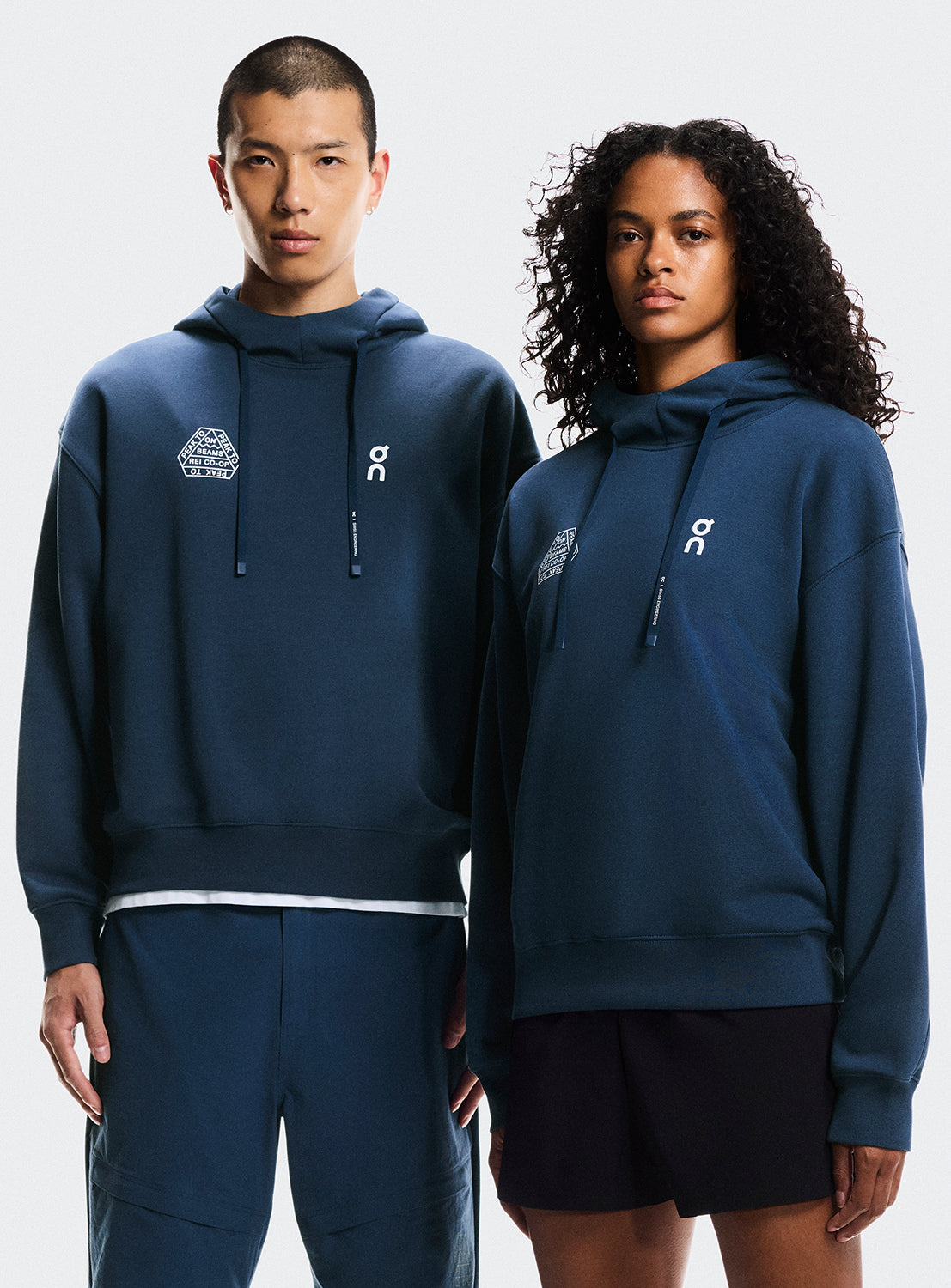 Two models wearing matching navy blue hoodies with the ON Running logo and BEAMS X REI CO-OP logo. 